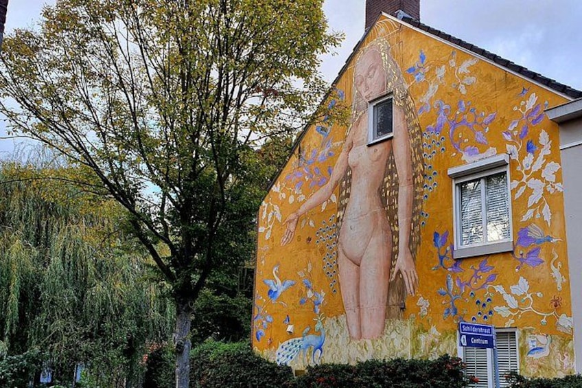 Un bâtiment orné d’une fresque représentant une femme et un arbre. 4
