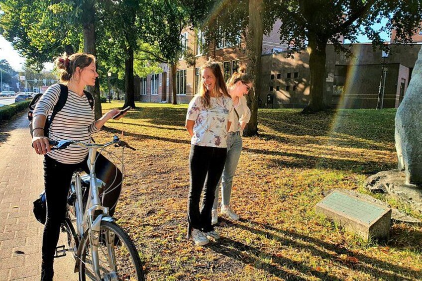 Trois personnes se tiennent sur un chemin dans un parc, avec des arbres et une statue en arrière-plan. 2