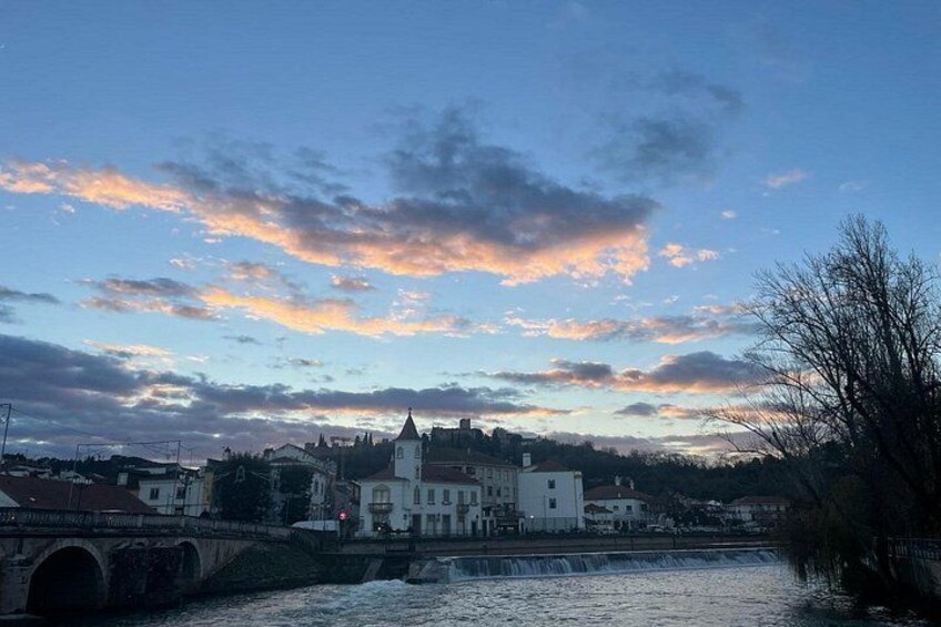 A bridge, a river, and buildings with a sunset sky. 2