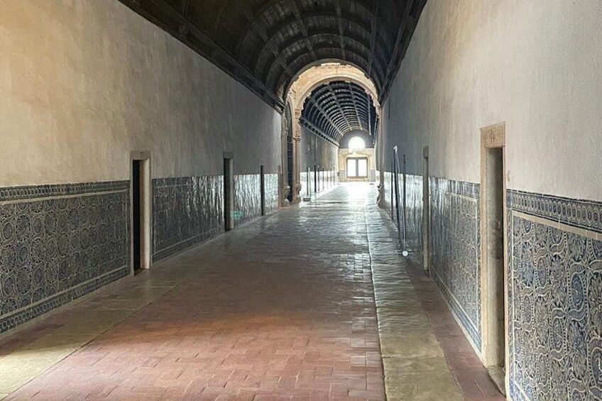 Un largo pasillo con paredes decoradas y piso de baldosas, que conduce a una puerta al final. 3