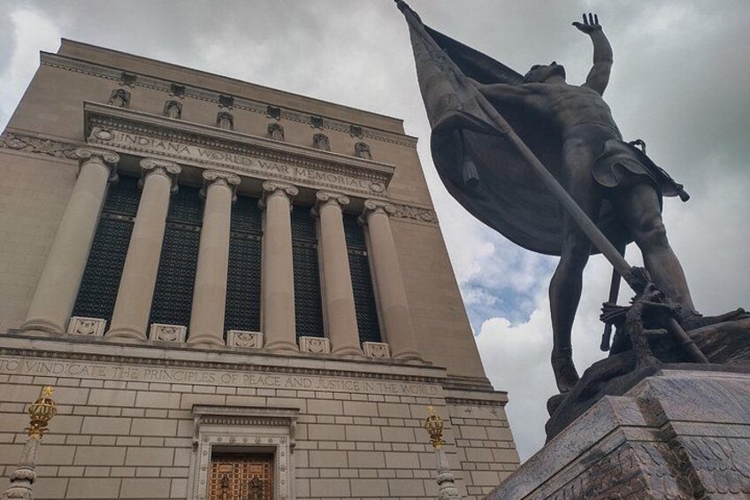 A large building with columns and a statue of a figure holding a flag. 4