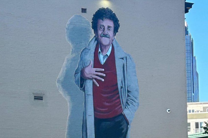 A mural of a man in a red shirt and gray jacket on a building wall. 2