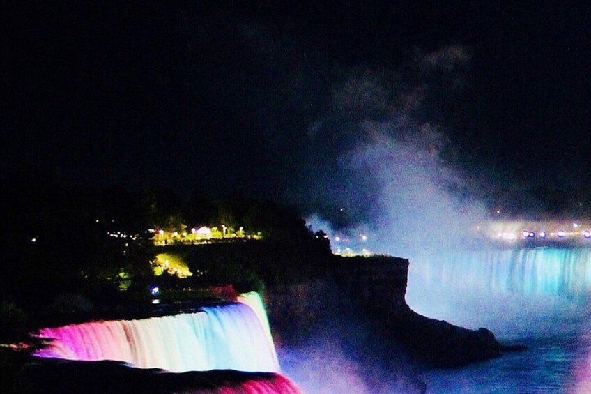 A waterfall at night with illuminated buildings in the background. 4