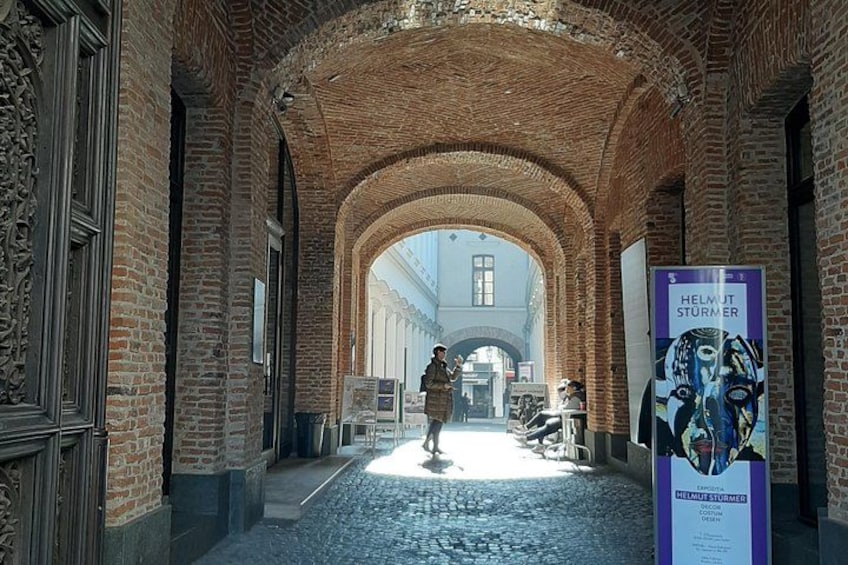 An arched brick corridor with a poster and a person walking. 3