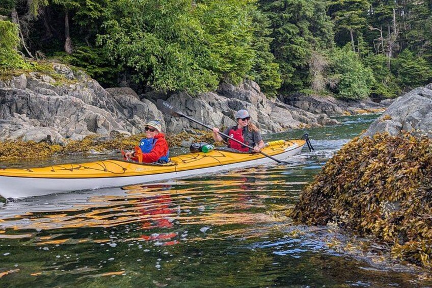 Two people kayaking on a river surrounded by rocks and greenery. 5