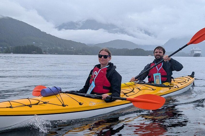 Two people kayaking on a calm lake with mountains in the background. 4