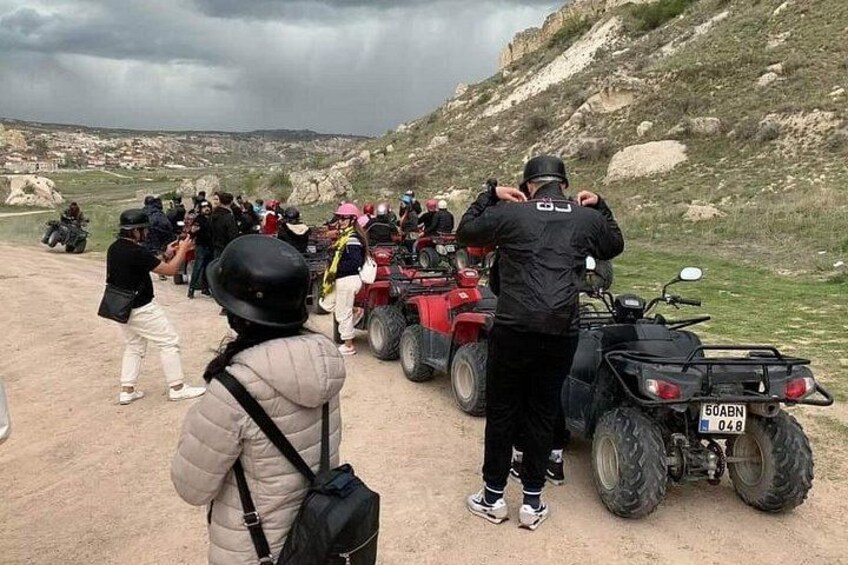 Un grupo de personas en vehículos todo terreno circulando por un sendero de tierra con un paisaje montañoso al fondo. 3