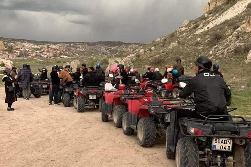 Un grupo de personas en cuatrimotos alineadas en un camino de tierra con un paisaje montañoso al fondo. 2