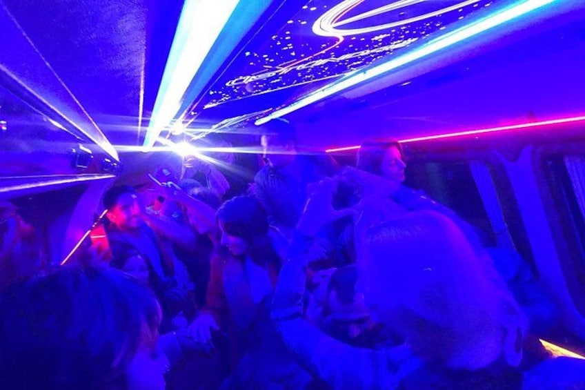 A crowded indoor space with people, neon lights, and a curved ceiling. 3
