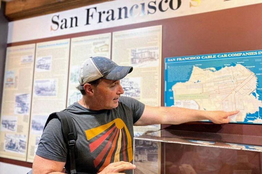 A man pointing at a map in a San Francisco exhibit. 4