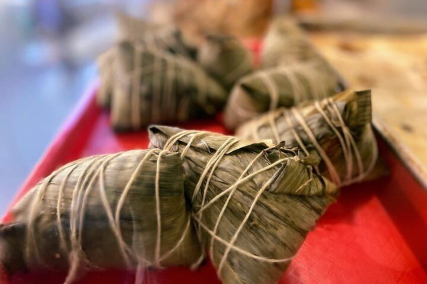 A tray of food wrapped in leaves, tied with string. 2