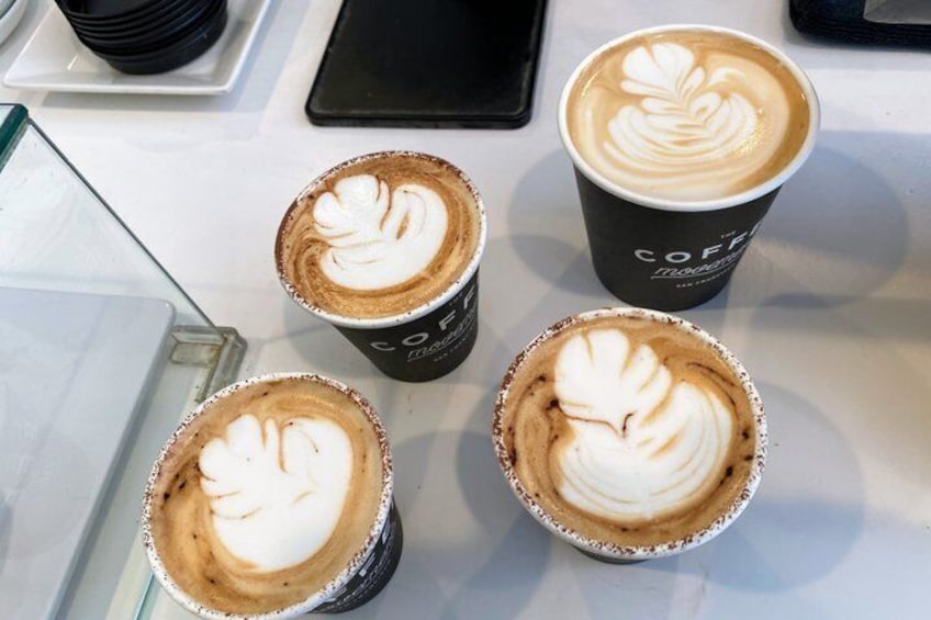 Four cups of coffee with latte art on a table. 3