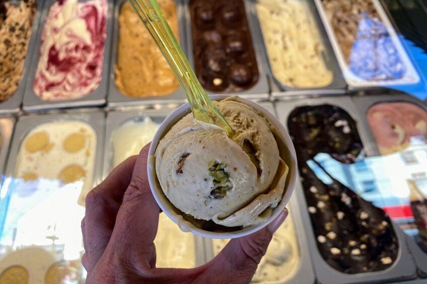 A hand holding a bowl of ice cream with a spoon. 5