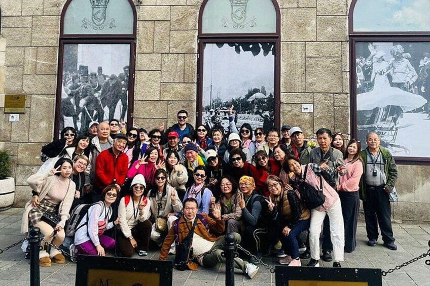 A group of people posing in front of a building with arched windows and a coat of arms. 3