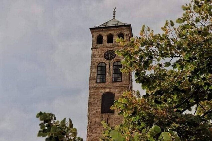A tall brick tower with a clock, surrounded by trees. 5