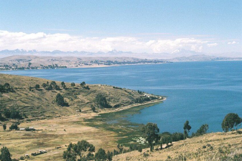 A coastal landscape with a clear sky, a large body of water, and distant mountains. 5