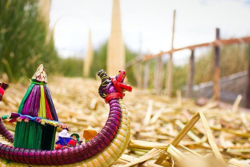 A colorful toy snake with a house and a figure on it, lying on straw. 2