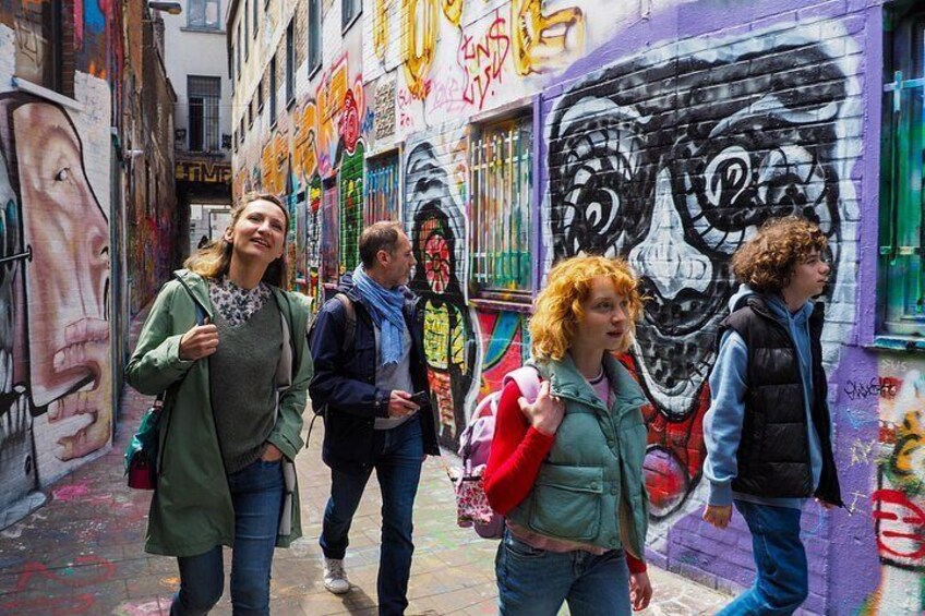 Un callejón estrecho con grafitis coloridos en las paredes, un mural de rostro y una gran obra de arte con calavera. 5