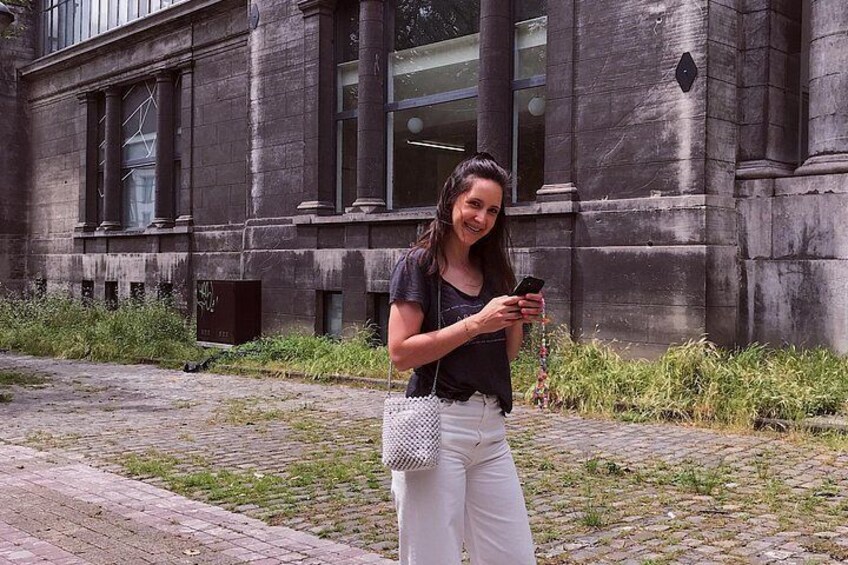 Una persona está de pie sobre un camino adoquinado frente a un edificio con grandes ventanales y columnas de piedra. 4