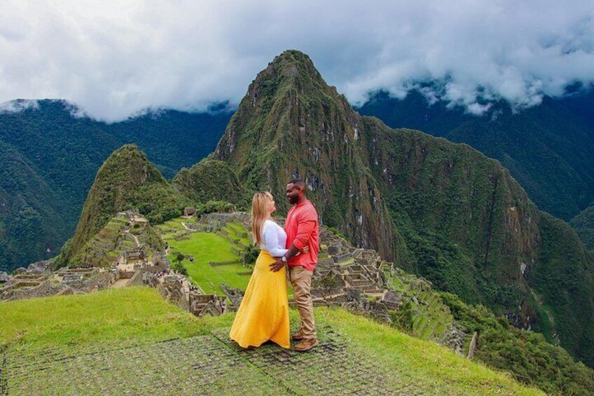 A couple embracing in front of Machu Picchu with the mountain range in the background. 1