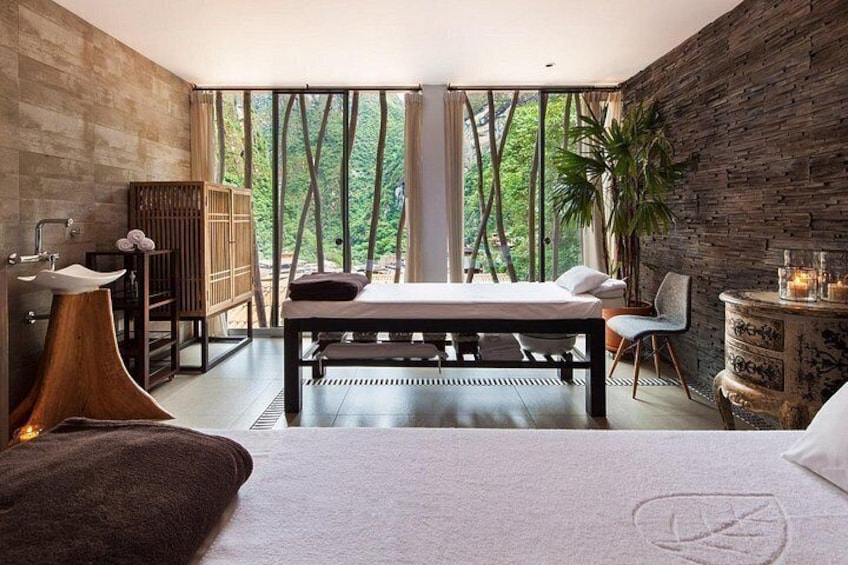 A bedroom with a large bed, a wooden cabinet, a plant, and a view of trees through the window. 2