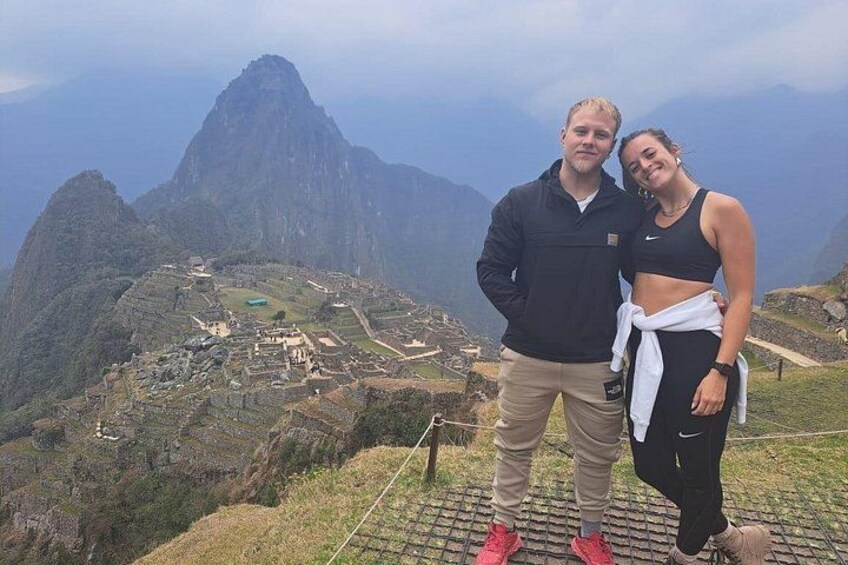 Deux personnes se tiennent debout sur une montagne, avec le Machu Picchu en arrière-plan. 5