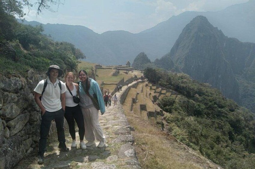 Un groupe de personnes se tient sur un chemin de pierre, avec les ruines du Machu Picchu en arrière-plan. 3