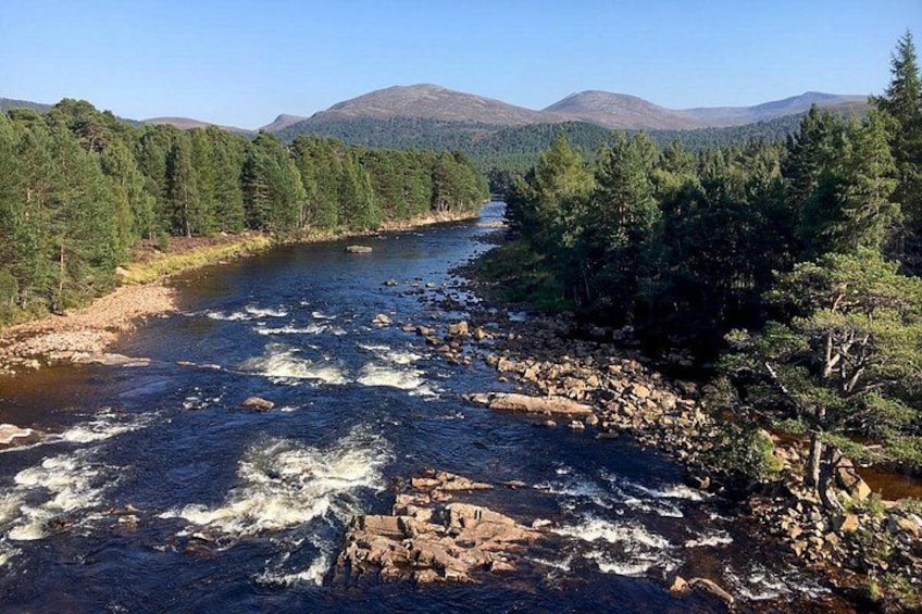Un río que serpentea por un valle boscoso con montañas al fondo. 2