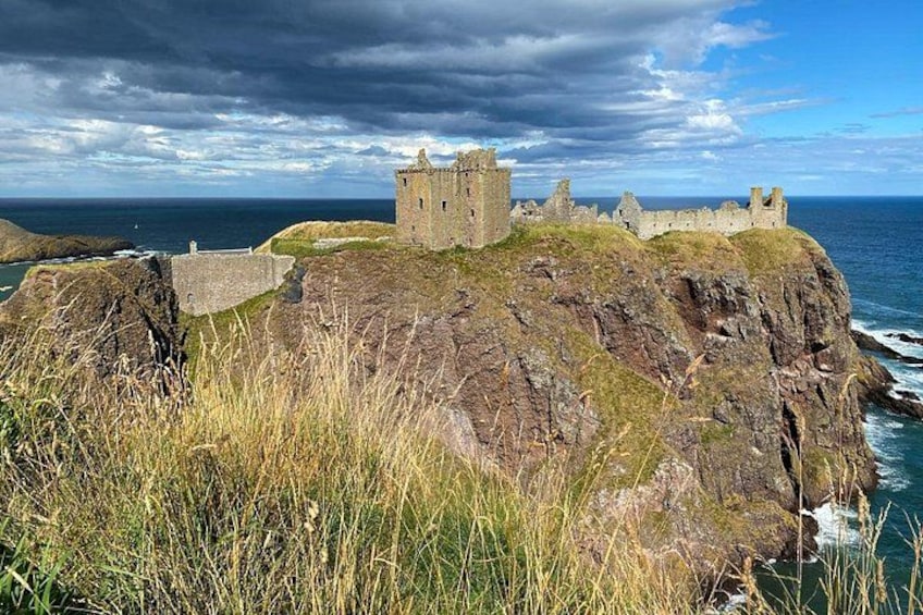 Un castillo costero sobre un acantilado rocoso, con el océano al fondo. 1
