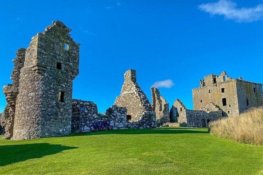 Ruinas de un castillo de piedra histórico con un césped bien cuidado. 4