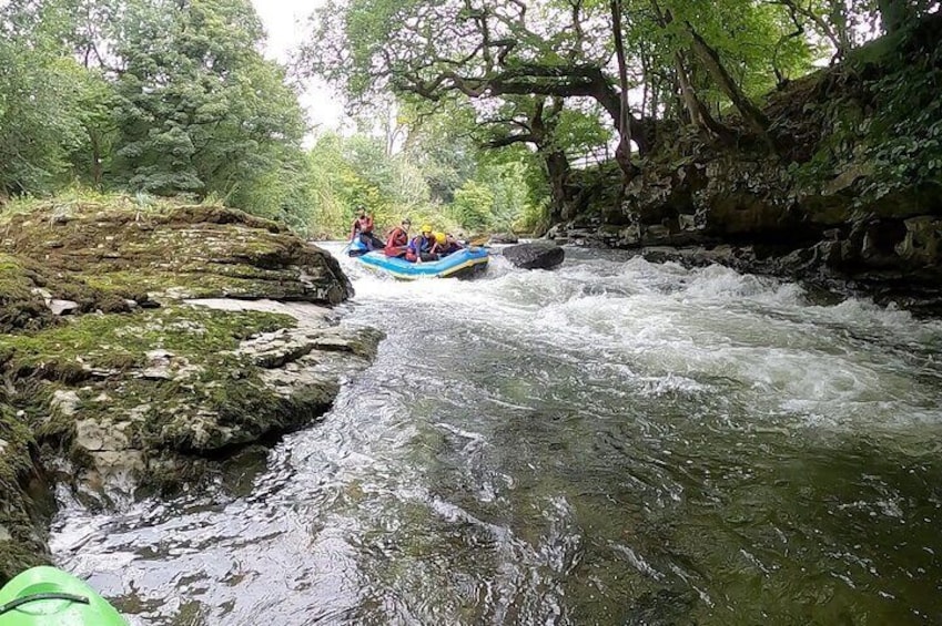 Un viaje de rafting por aguas bravas a través de un río arbolado con orillas rocosas y exuberante vegetación. 4