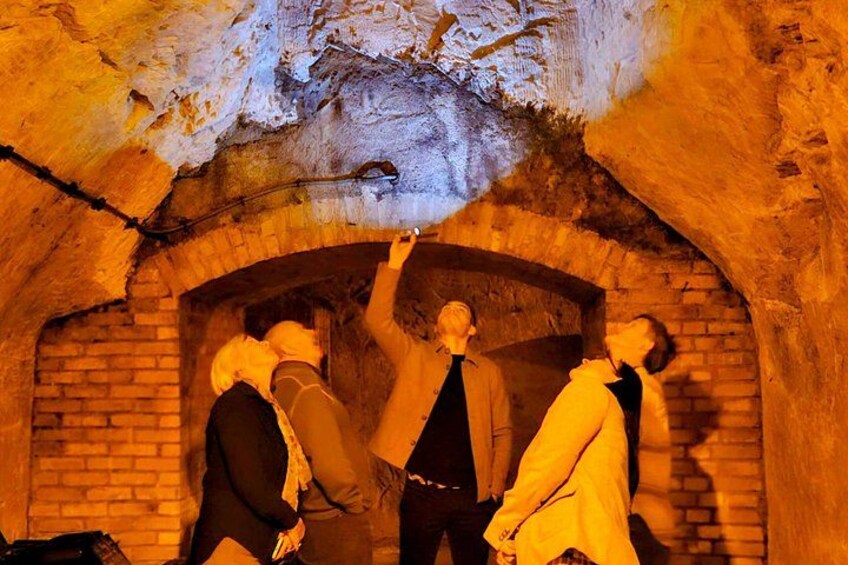 A group of people in a dimly lit, arched brick structure. 3