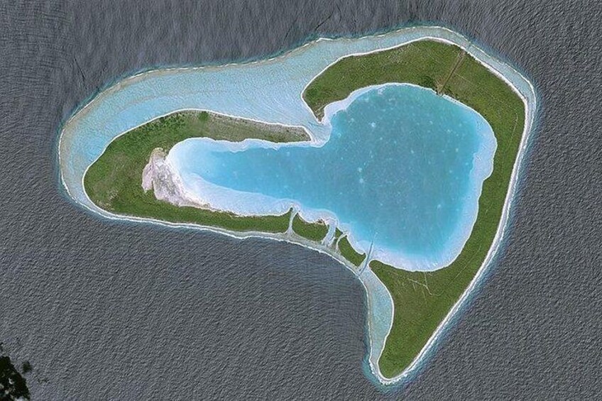 Vista aérea de una pequeña isla con una laguna central, rodeada por un estrecho canal de agua y una masa de agua más extensa. 2