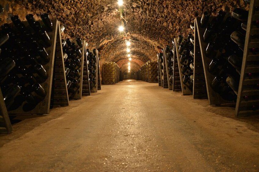 A wine cellar with rows of wine bottles on racks. 3