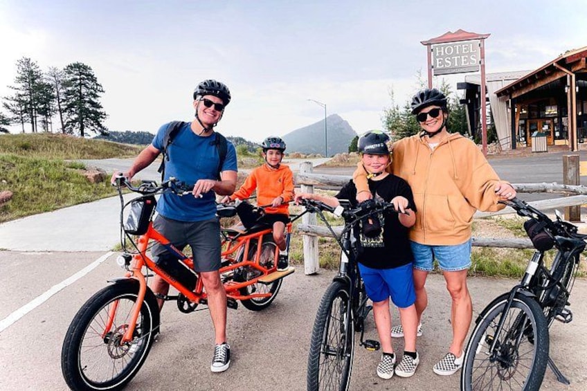 A group of people on bicycles near a sign that reads 'HOTEL ESTES.' 3