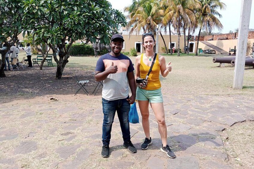 Two people standing on a paved area with trees and a building in the background. 2