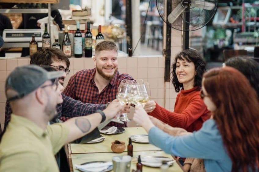Eine Gruppe von Personen stoßt in einem Restaurant mit Weingläsern an. 1
