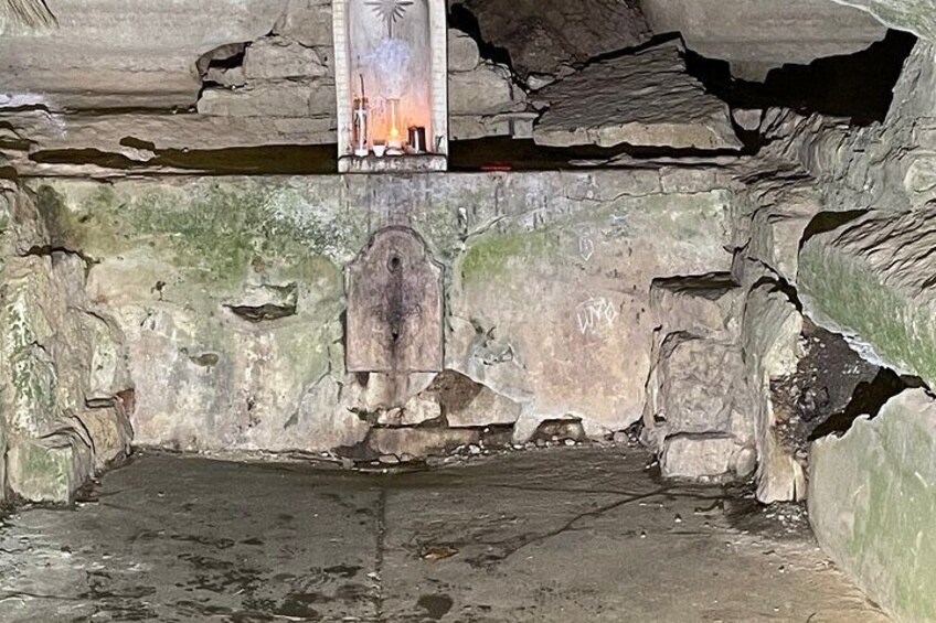 A cave interior with stalactites, a wooden structure, and a mural. 5