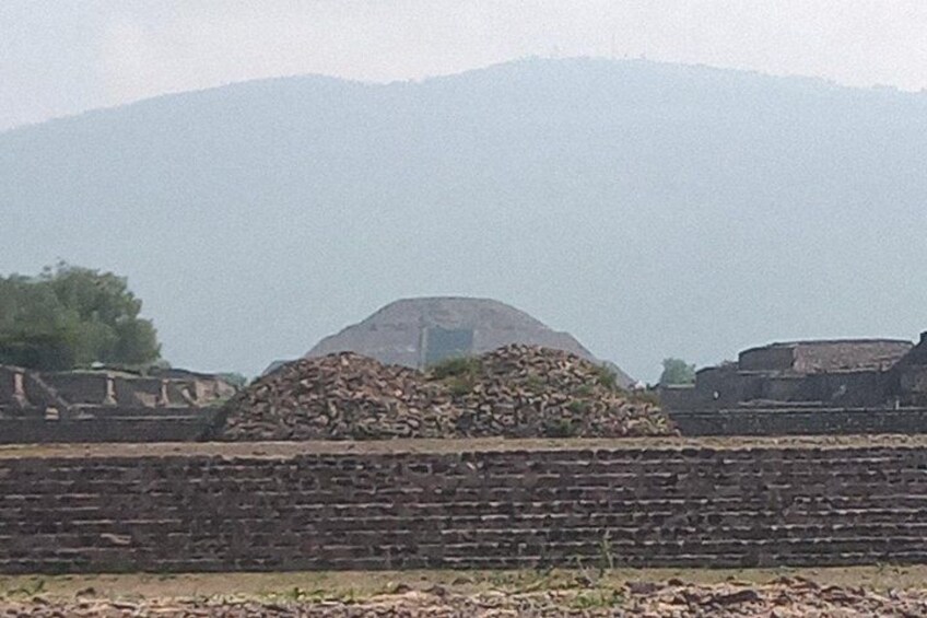 A historical site with a large mound, a brick wall, and a pile of stones. 3