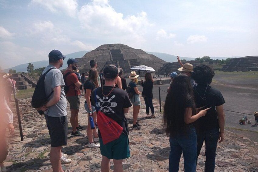 A group of people standing on a rocky terrain with a large pyramid-like structure in the background. 4