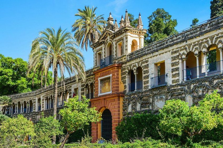 A historic building with ornate architecture, palm trees, and a clear blue sky. 1