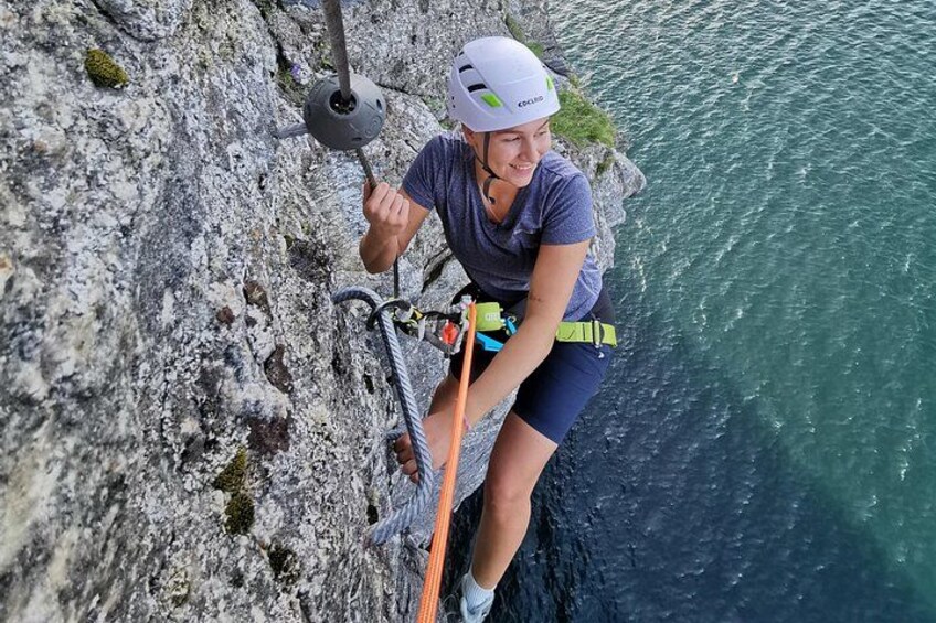 A person rappelling down a rocky cliff near a body of water. 1
