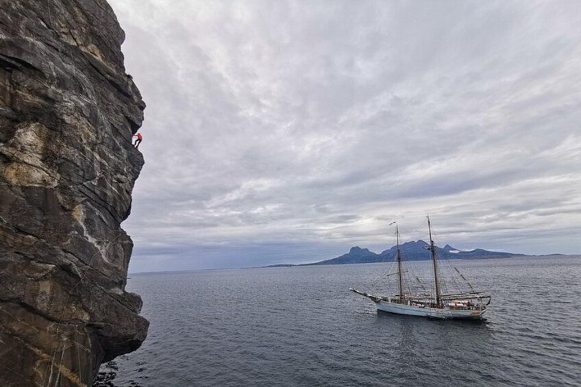 A rocky coastline with a boat on calm waters, a distant mountain, and overcast skies. 2