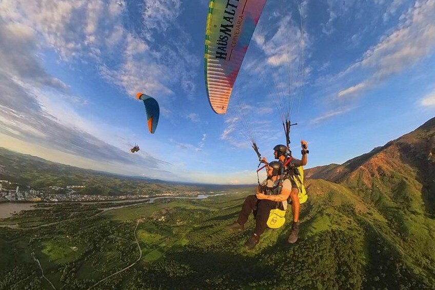 A person paragliding over a mountainous landscape with a banner in the sky. 5