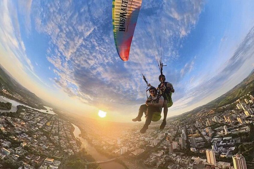 A person paragliding over a cityscape at sunset. 4
