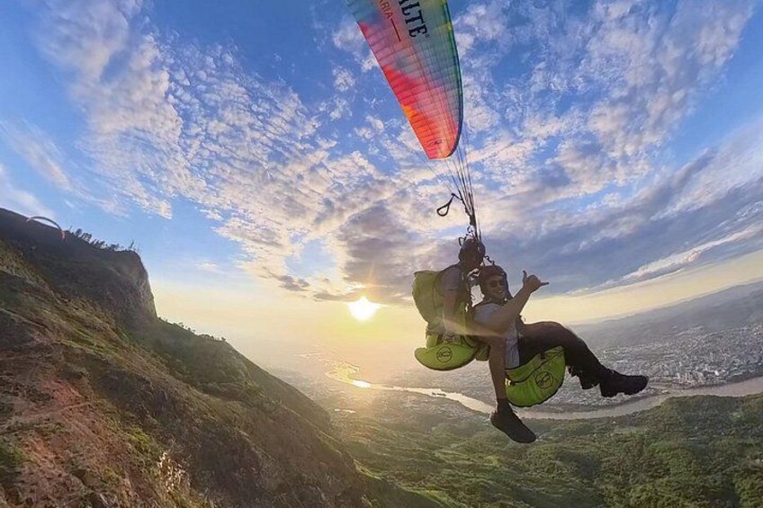 A person paragliding over a landscape with a view of the city below. 1
