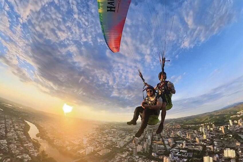 A person paragliding over a cityscape during sunset. 2