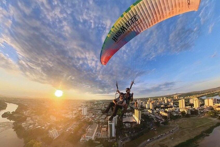 A person paragliding with a colorful canopy over a cityscape at sunset. 3