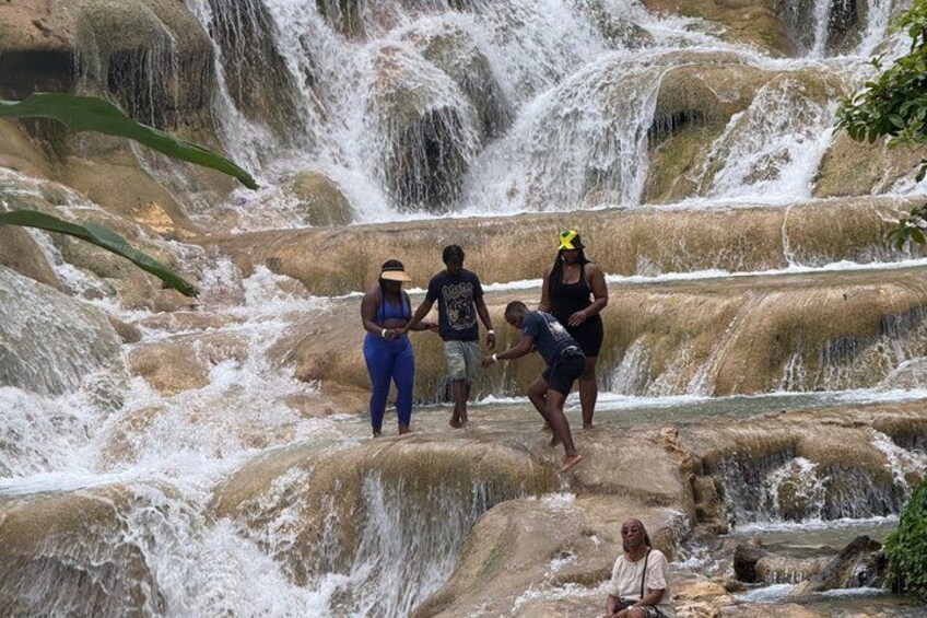 A group of people near a cascading waterfall with rocky terrain. 4