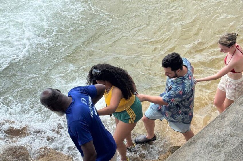 People standing at the edge of a river, some holding onto a railing. 2